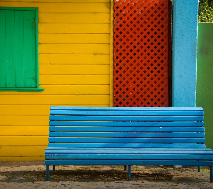 Blue bench in front of colorful wooden wall