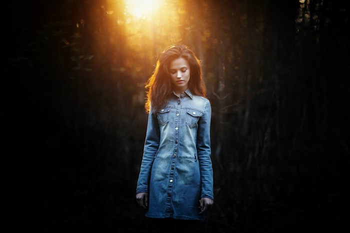 Woman in denim dress in sunlit forest