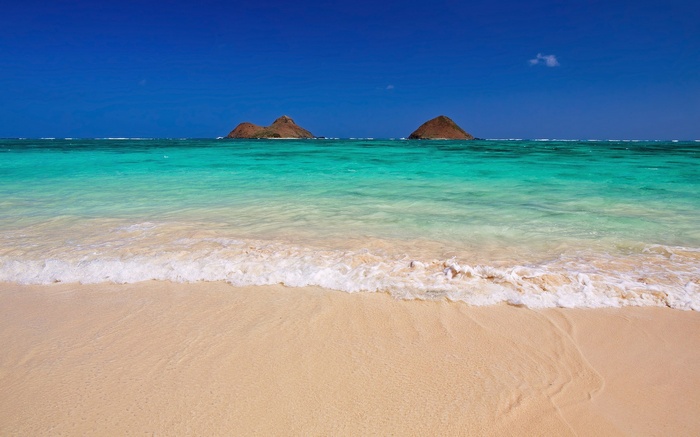 Two islands in the ocean with a beach and waves