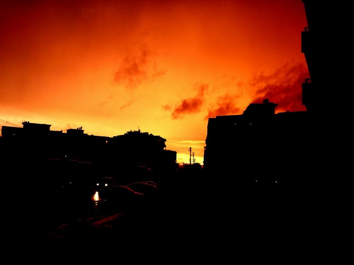 Silhouette of buildings against a fiery sunset sky