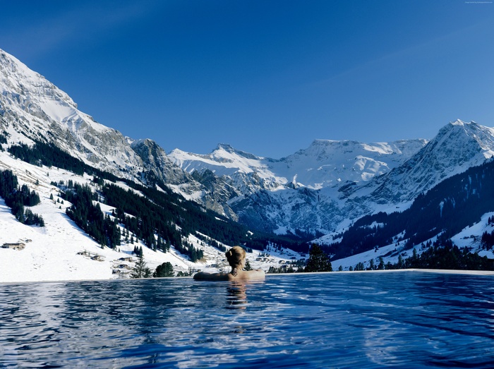 Infinity pool overlooking snowy Swiss mountains