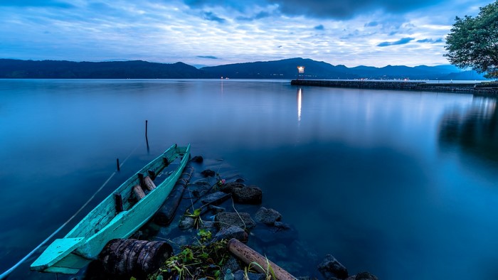 Turquoise boat on a calm lake at dusk