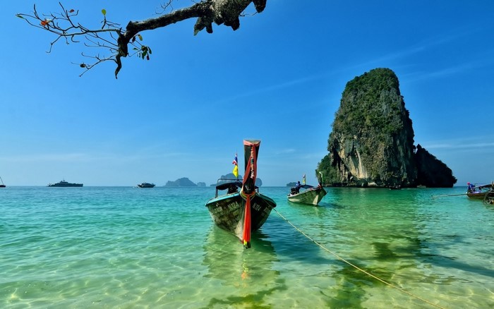 Longtail boats in a tropical bay with a large rock island