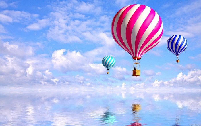 Hot air balloons floating over a reflective body of water
