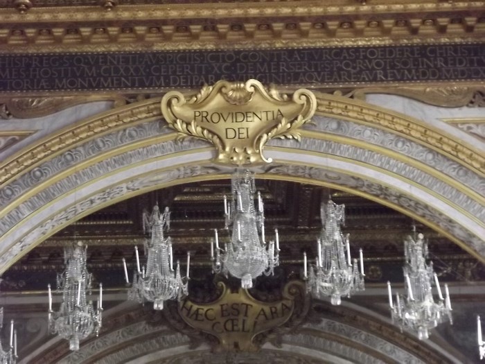 Interior of a grand building with chandeliers and Latin inscriptions