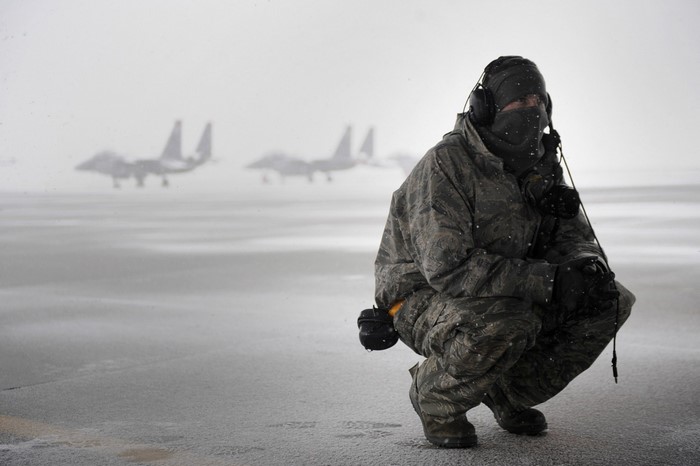 Military personnel in snow with fighter jets