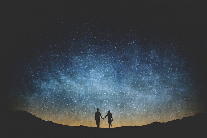 Couple holding hands under the Milky Way