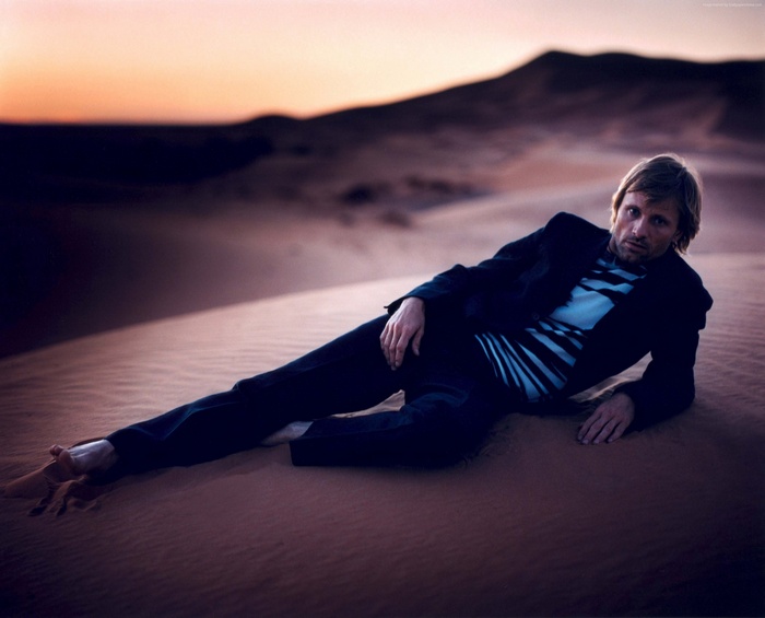 Viggo Mortensen lying on a sand dune at sunset