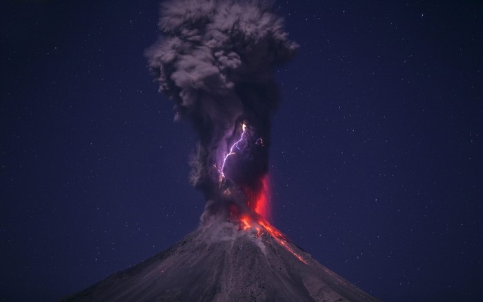 Volcano erupting with lightning at night