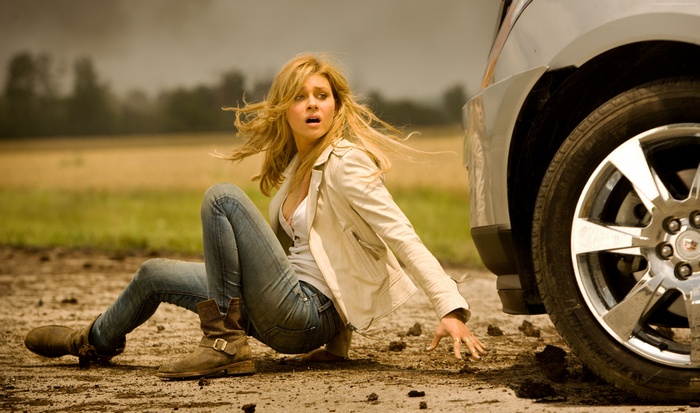 Nicola Peltz sitting on the ground next to a car