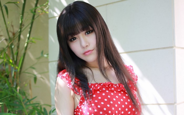 Young woman with long black hair in a red polka dot dress