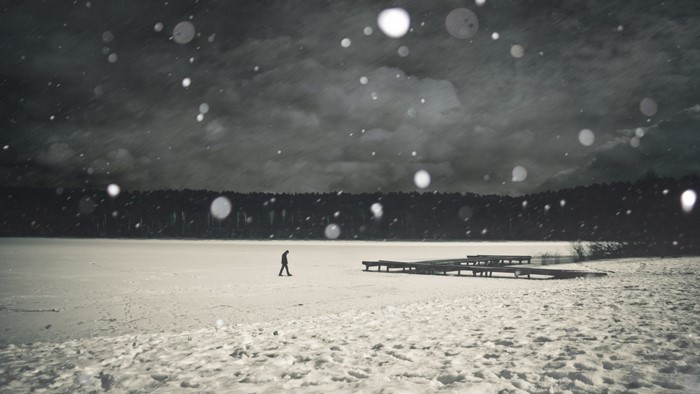 Person walking on a frozen lake during snowfall
