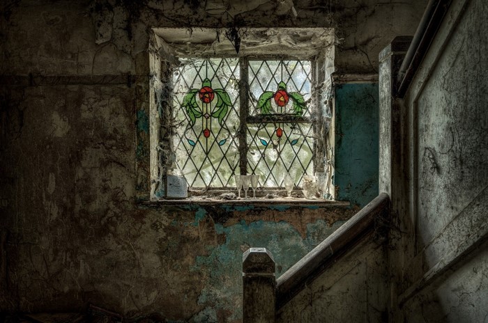 Abandoned house with stained glass window and staircase