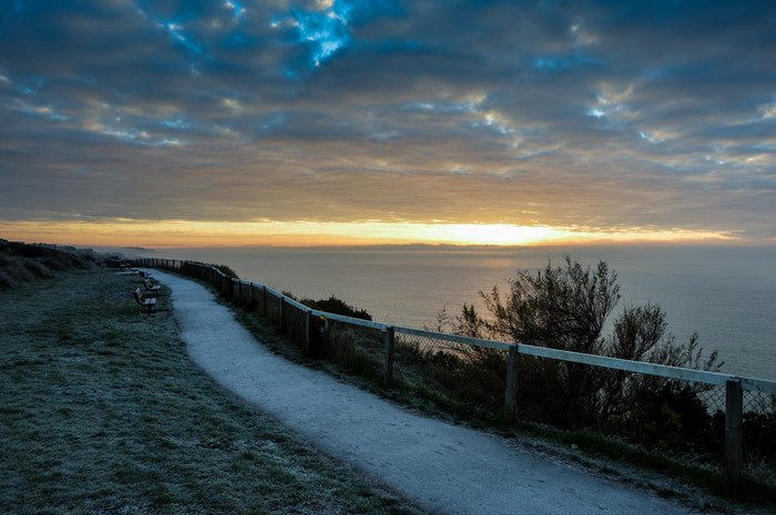 Coastal path at sunrise with frosted grass and ocean view