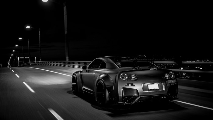 Modified Nissan GT-R driving on a bridge at night