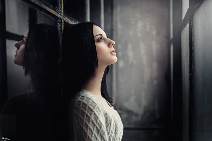 Woman leaning against a window frame, looking up