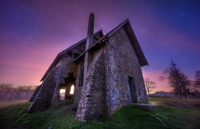 Ruined stone church under a starry purple and pink sky