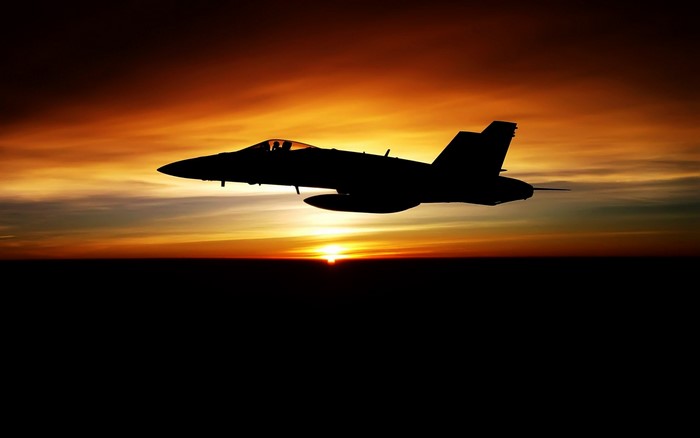 Silhouette of FA-18 Hornet fighter jet at sunset