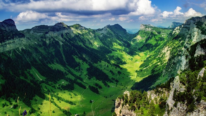 Sunlit Alpine Valley with Mountain Range and Meadow