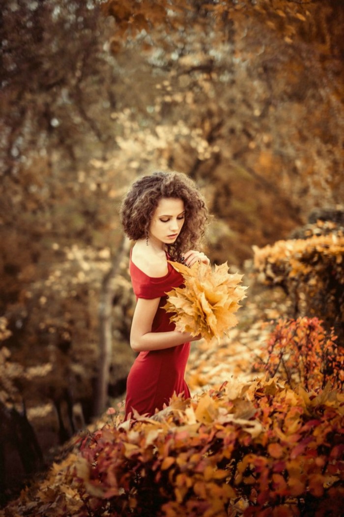 Woman in red dress holding autumn leaves