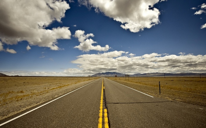 Empty desert highway with mountains in the distance