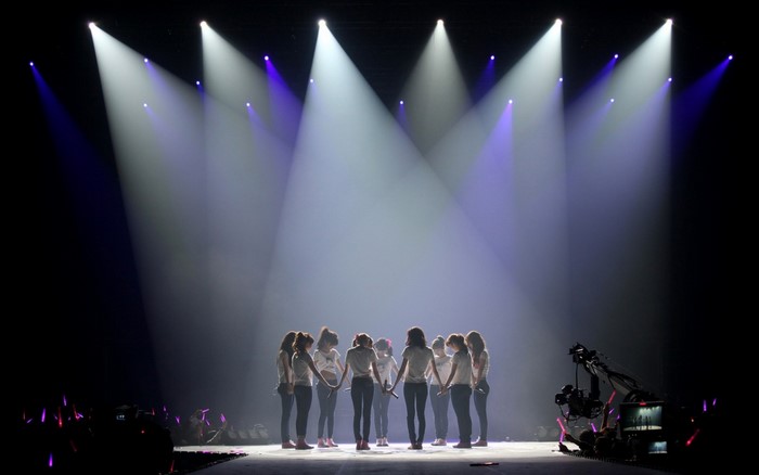 Girls Generation performing on stage with spotlights