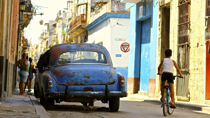 Boy on bicycle near vintage car in Havana, Cuba
