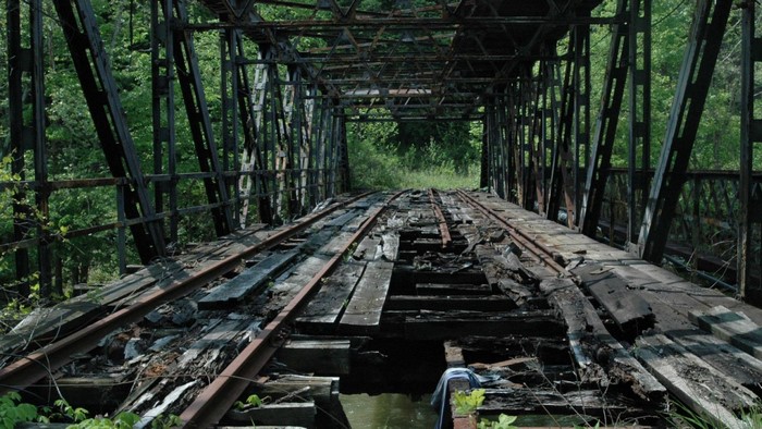 Abandoned railway bridge overgrown with trees