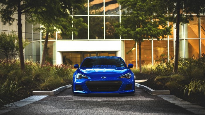 Blue Subaru BRZ sports car parked in front of a modern building