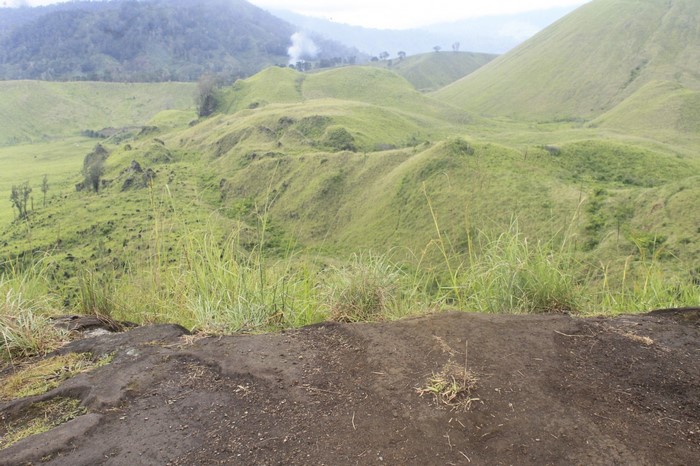 Rolling green hills and rocky terrain under a cloudy sky