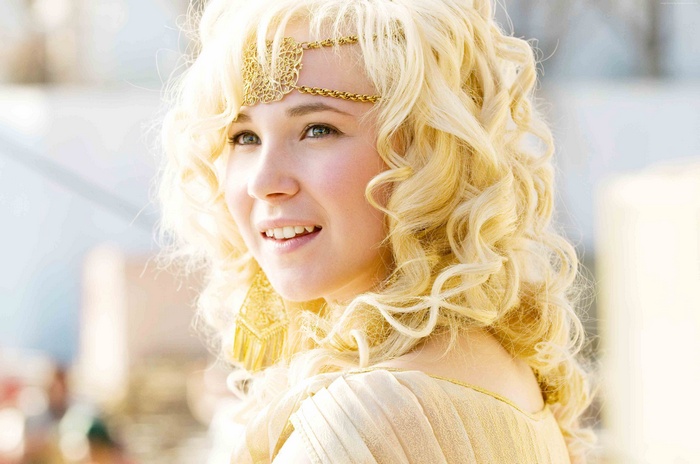 Juno Temple as a blonde woman with golden accessories