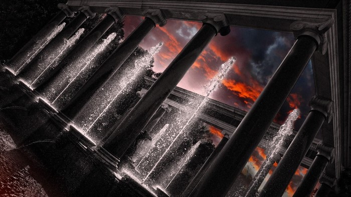 Columns and fountains against a dramatic sunset sky