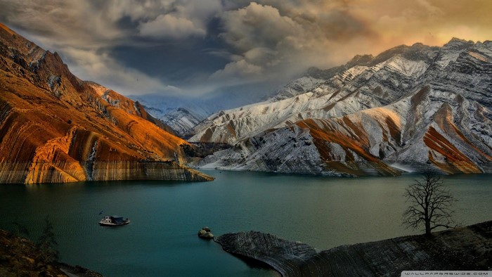 Mountains and lake with a boat at sunset