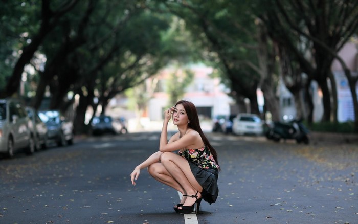 Elegant Woman Posing on Tree-Lined Street