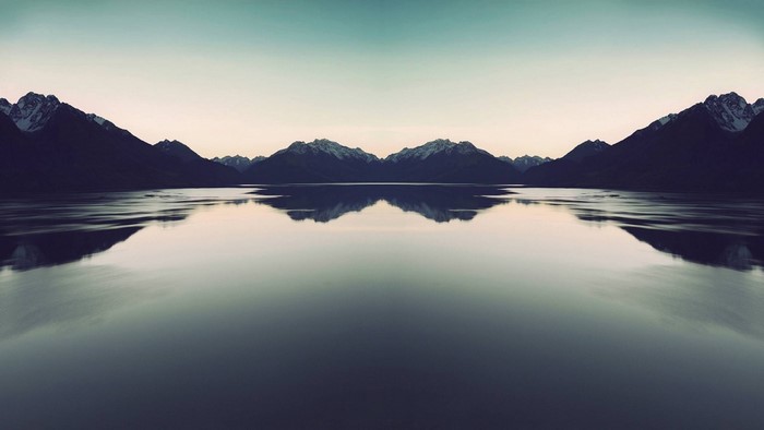 Mirror image of mountains reflecting in a calm lake at dawn