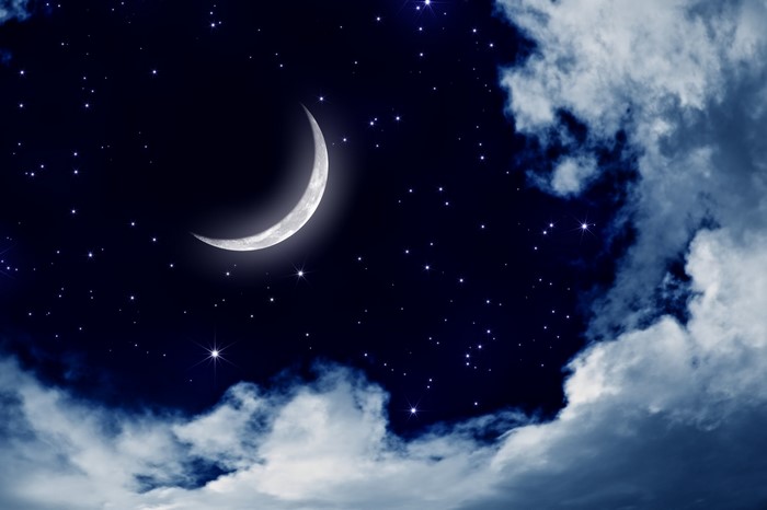 Crescent moon in a starry night sky with clouds