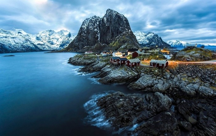 Coastal village with red houses and snowy mountains in Norway