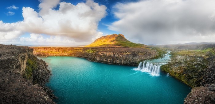 Turquoise lake with waterfall and mountain in Iceland