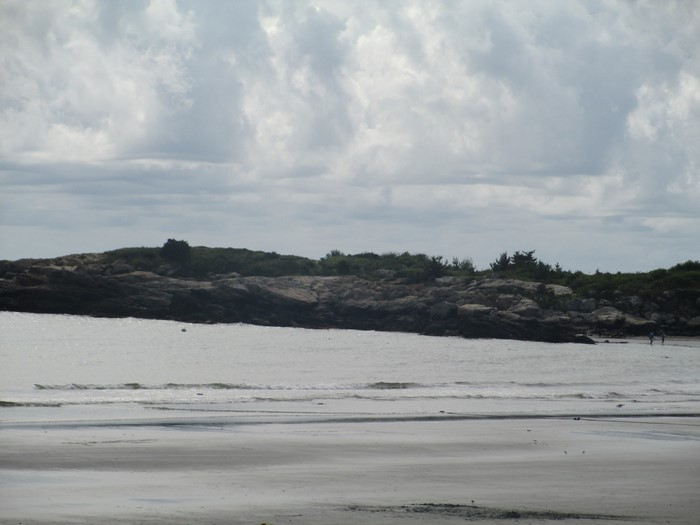 Rocky coastline with beach and cloudy sky