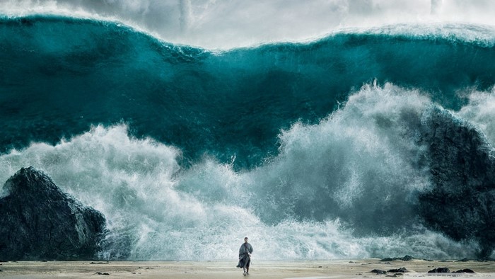 Man walking on beach with massive waves crashing