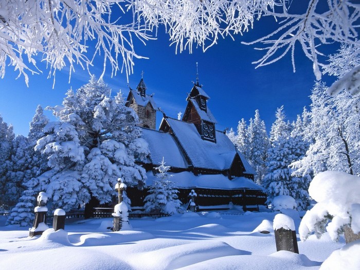 Snow-covered church in a winter forest with frosted branches