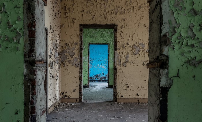 Abandoned building interior with peeling paint and doorways