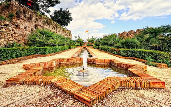 Garden with star-shaped fountain and stone wall