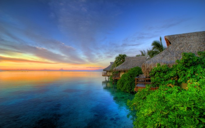 Overwater bungalows at sunset over the ocean