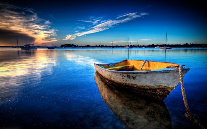 Boat on calm water at sunset with reflections