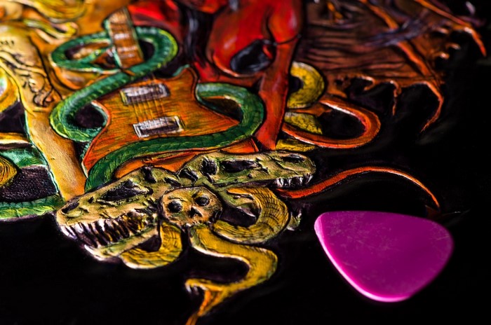 Illustration of a guitar entwined with a snake and skulls