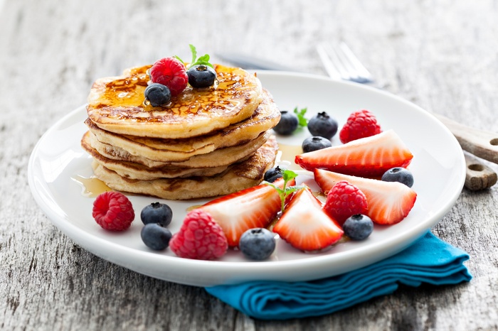 Pancakes with berries and honey on a plate