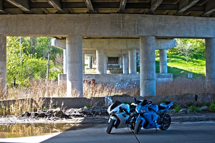 Two sport motorcycles parked under a concrete overpass