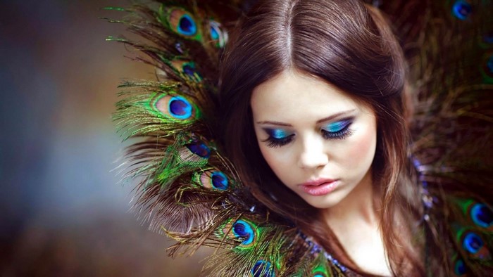 Woman with peacock feathers and blue makeup