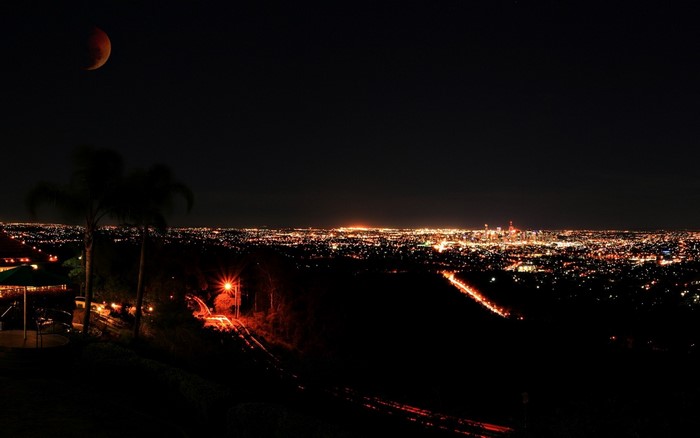Lunar eclipse over a city skyline at night